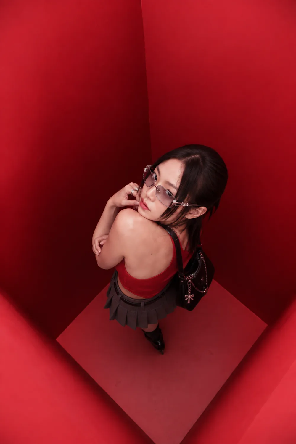 A guest in glasses photographed from directly above inside the red booth, turning back over her shoulder to look up at the camera.