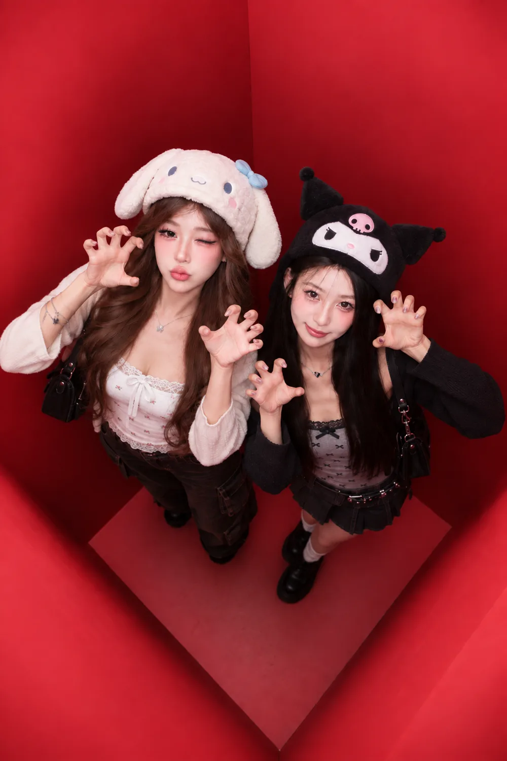 Two guests in soft character hats photographed from directly above inside the red booth, both holding their hands up like claws.